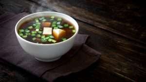 miso soup in white bowl on the wood table and dark napkin