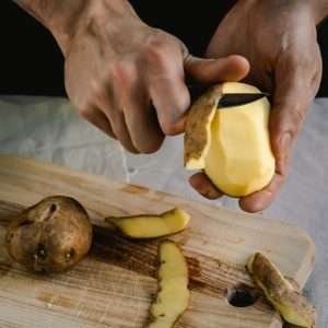 hand peeling potato with small knife